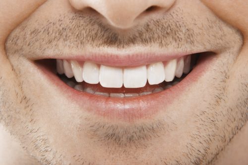 Close-up of smiling bearded man's white teeth