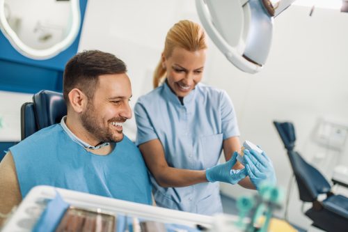 Dentist showing patient model of his teeth in dental exam room