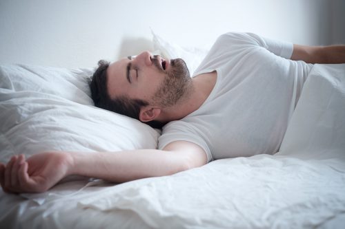 Man laying in bed snoring loudly