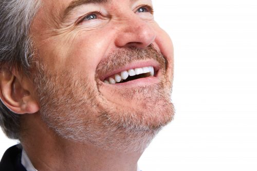 Bearded man with white teeth looking up and smiling