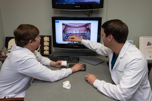 Dentists analyzing photo of teeth in mouth on large monitor